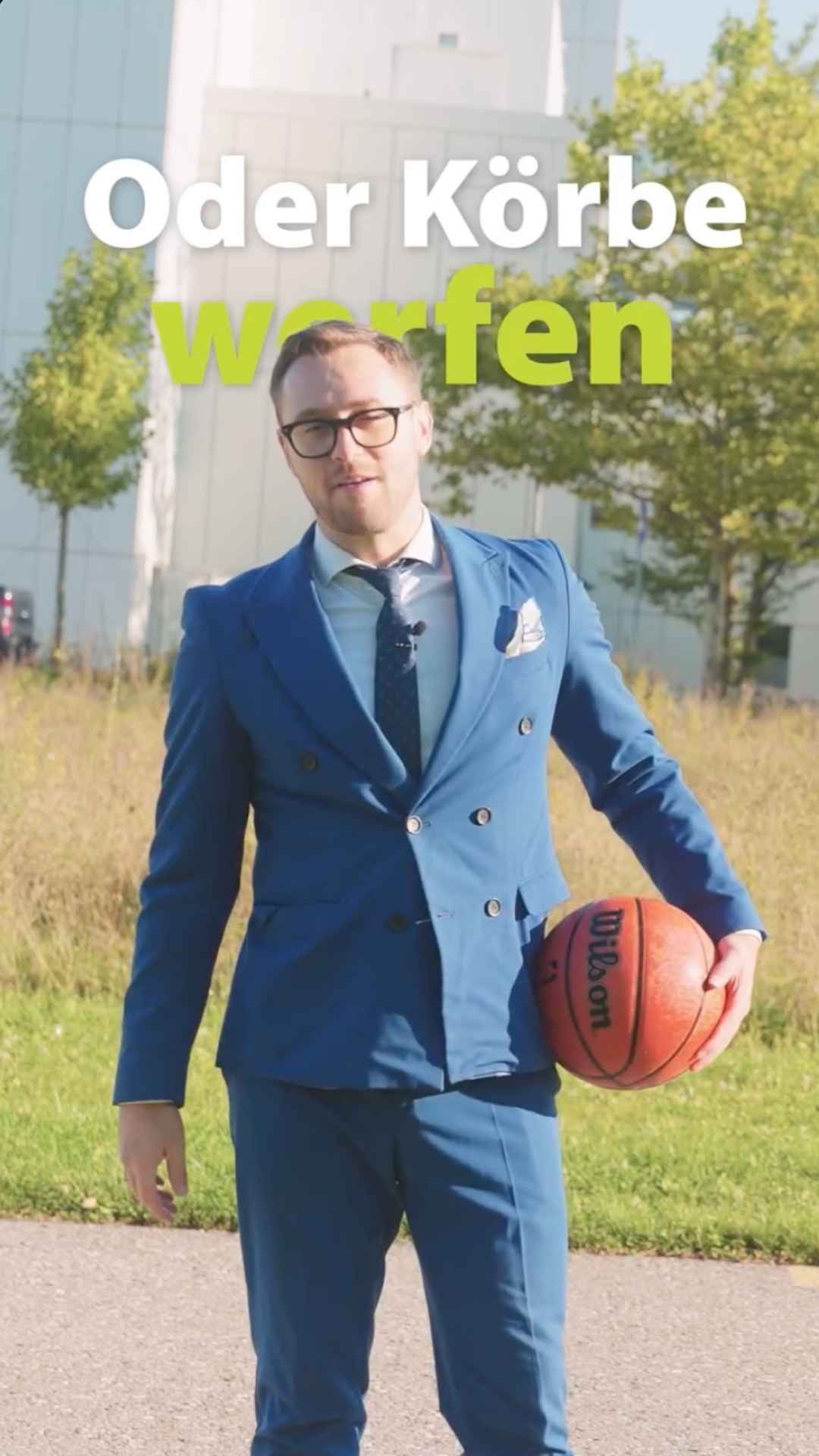 Mann mit blauem Anzug und Basketball in der Hand.
